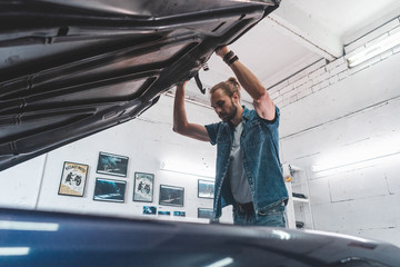 Attractive Caucasian man carrying out maintenance of his old vintage retro car