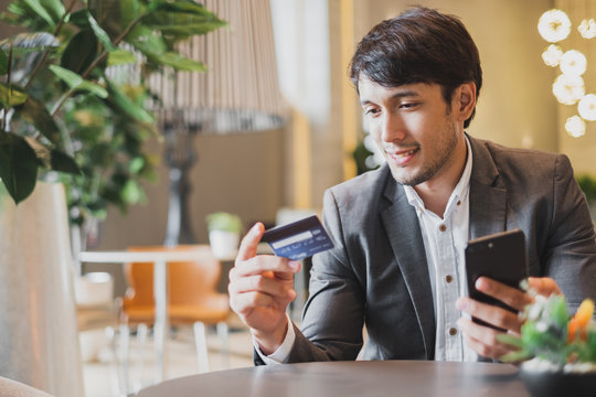 Asian businessman using credit card and mobile phone for online financial payment and shopping