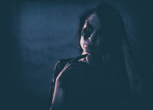 a young succubus girl on a smoke background with hands stained with soot and a burned face with an expressive look and a pleasant appearance in a black dress