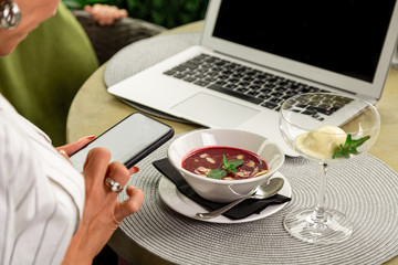 Businesswoman working during the lunch with salad sitting at the vegan restaurant on the beautiful green wall background