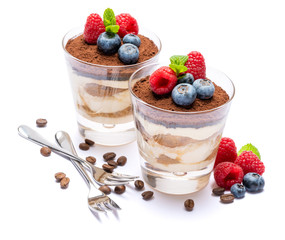 Classic tiramisu dessert with blueberries and raspberries in a glass isolated on a white background with clipping path