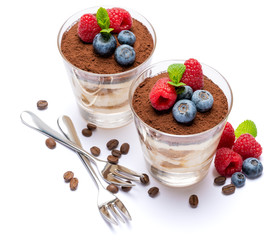 Classic tiramisu dessert with blueberries and raspberries in a glass isolated on a white background with clipping path