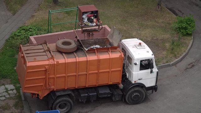 Garbage truck takes out loads a container with garbage