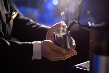The shot of the hand that is caught in the milk bubble. The coffee shop Barista is preparing hot milk in an espresso machine.