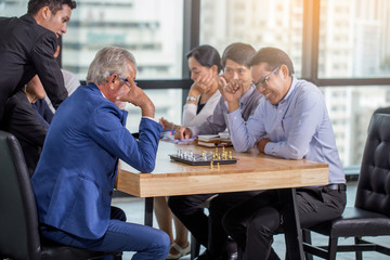 The senior boss plays chess with the staff in the meeting room during the break.