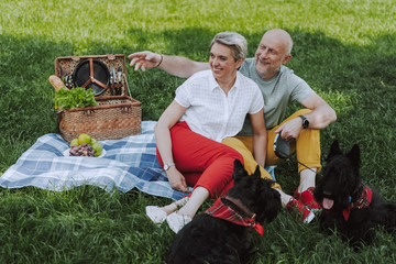 Smiling adult couple sitting on the plaid in the park