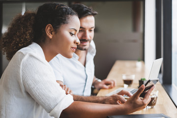Young man and woman working on laptop and using mobile phone relax in business office