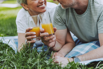 Smiling wife and husband drinking juice in the park together