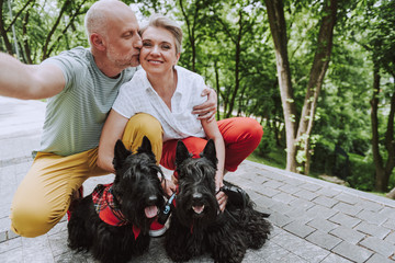 Happy adult couple with two black dogs in park