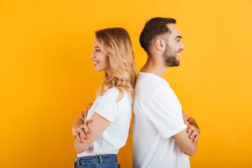 Image of young people man and woman in basic t-shirts smiling while standing back to back