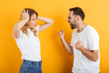 Image of resentful couple man and woman in basic t-shirts screaming at each other during fight