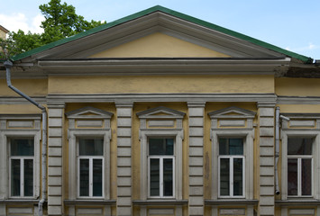 Facade of an old yellow building with five windows and a sloping roof