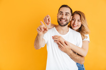 Image of pretty couple man and woman expressing wonder while pointing fingers aside at copyspace