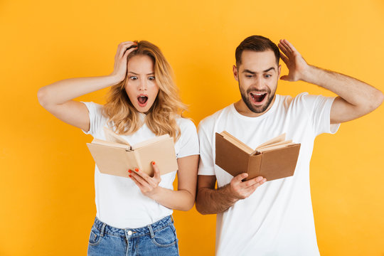 Image of shocked couple man and woman expressing wonder while reading books together