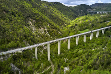 Bridges with cars over green hilly valley