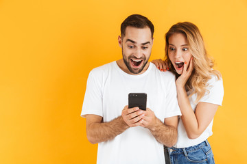 Image of amazed couple man and woman wondering while looking at cellphone together