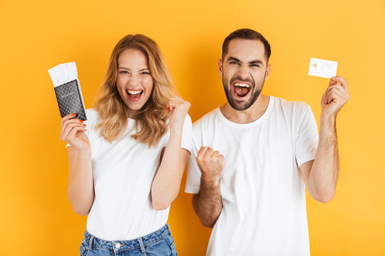 Image of delighted couple rejoicing while holding credit card and passport with travel tickets