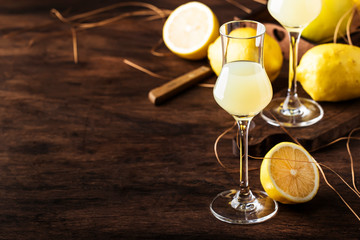 Limoncello, sweet Italian lemon liqueur, traditional strong alcoholic drink. Still life in vintage...