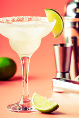Lime margarita alcoholic cocktail with silver tequila, liqueur, lime juice, sugar syrup, salt and ice, festive trendy pink background, copy space