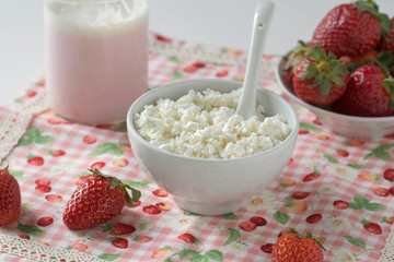 Cottage cheese in a white cup with a spoon, strawberry yogurt and fresh strawberries on a napkin