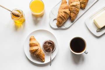 Freshly baked croissants and cup of coffee on white. Space for text. French breakfast.