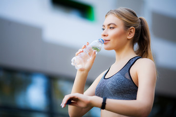 Fitness women. Woman drinking water from bottle in nature