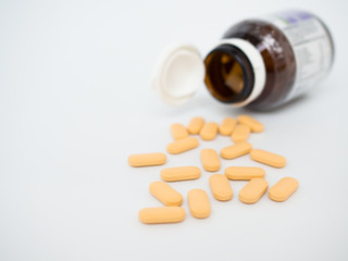 pills spilling out of pill bottle on white background