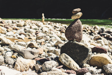 zen stones in equilibrium pyramid at a pebble river beach - concept of equilibrium with nature