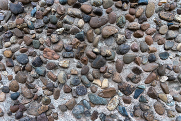 Concrete plaster interspersed with many smooth river stones. Decorative wall.