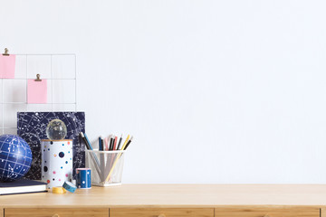 Cosmic and stylish home office interior with wooden desk, cool office accessories, tapes, supplies,...