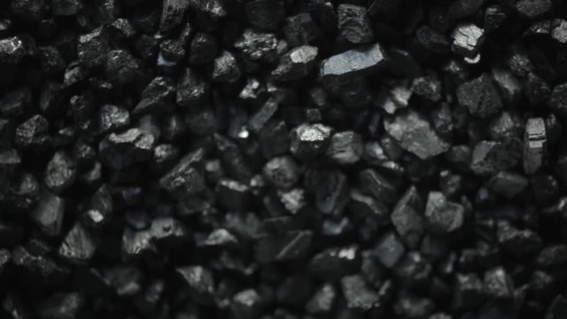 Black coal stones shaking and moving forward through vibrations of sound. Natural coals, macro shot.