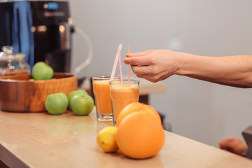 Two servings of fruit juice with a straw in glass cups stand on the bar near the fruit vases. Detox cleansing concept