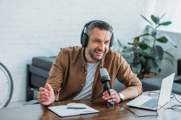handsome radio host smiling while speaking in microphone in broadcasting studio
