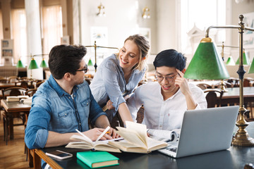 Smart cheerful teenagers studying at the library together