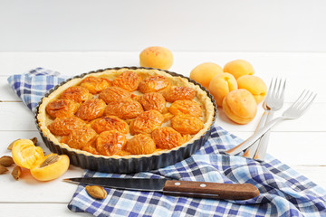 Homemade apricot pie with fresh fruits on white wooden table. Shallow focus.