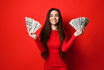 Young pretty woman in red dress hiding behind bunch of money banknotes