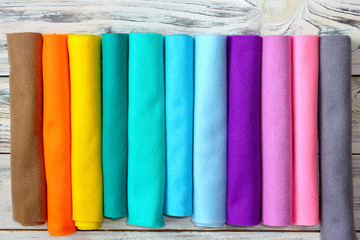 Rolls of bright colored felt fabric on a white wooden background