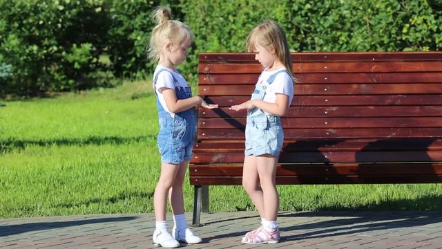 Two little girls meet in the street. Meeting two girls 5 years of age in the park.