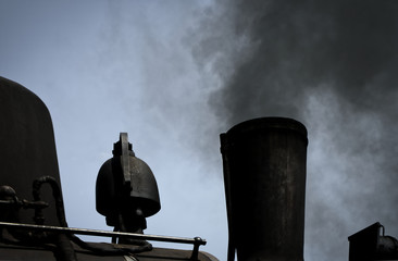 Detailed view of a black historic steam locomotive blowing black rusty smoke out of a chimney, transport, black and white