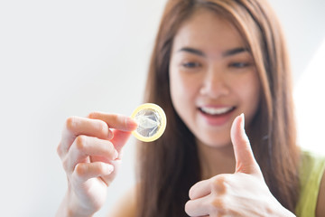 Young woman holding condom prevent pregnancy