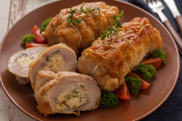 Stuffed chicken roll s vegetable garnish and herbs.