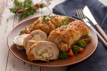 Stuffed chicken roll s vegetable garnish and herbs.