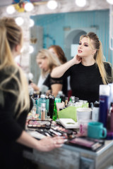 Woman in a beauty salon looks at her reflection in the mirror on her makeup and hairstyle.