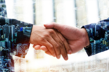 Deal. double exposure image of young businessman investor shaking hands with partner during new project contract with city background,  investment, business negotiating, partnership, teamwork concept