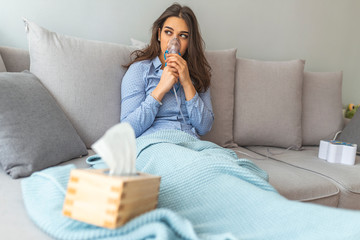 Woman using asthma machine at home. Sick beautiful female in blue cloth hold nasal mask with...