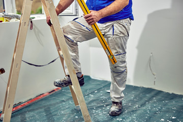 Worker standing on the ladder and renovating house.