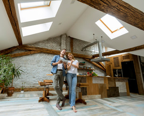 Young couple eating pizza and using digital tablet by the table in the rustic apartment