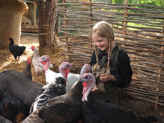 Village girl sitting among farm animals. Portrait of child