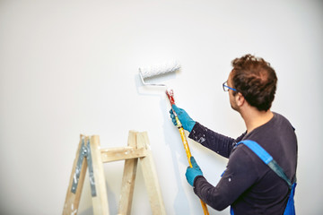 Worker painting walls inside the house - renovation fixes.