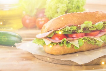 Sandwich with ham and vegetables on wooden board